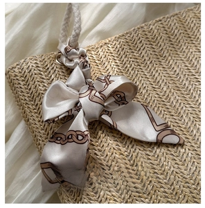 Détail du sac en paille beige avec nœud en soie champagne et poignée en corde de coton blanc