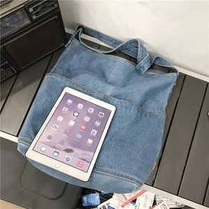 Large washed denim tote bag in light blue shown holding an iPad for scale
