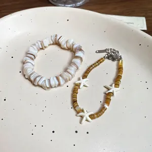 Irregular shell beaded bracelet and starfish charm necklace set on ceramic tray