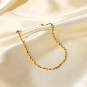 Détail d'un bracelet en chaîne à billes ovales plaqué or 18 carats sur de la soie crème