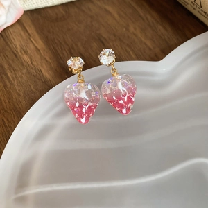 Detail view of pink resin strawberry earrings with sparkling glitter and gold hooks
