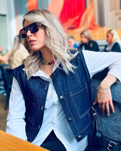 Detail of dark blue denim vest with contrast stitching and multi-pocket design on a model