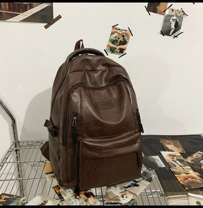 Dettaglio dello zaino in pelle PU marrone con scomparti a cerniera e marchio CLED BAG