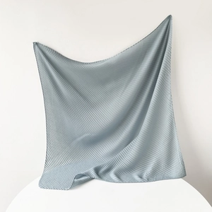 Detail of light blue square scarf featuring delicate pleated texture and soft fabric