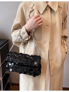 Elegant black sequin handbag with silver chain strap worn over a beige trench coat