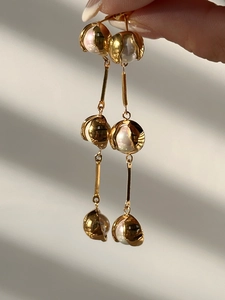 Macro view of long vintage 18k gold plated drop earrings with white pearls and shell cups