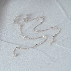 Macro detail of S925 sterling silver long tassel chain earrings on stone texture background