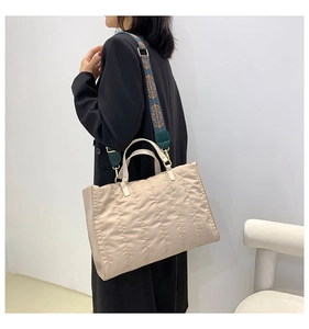 Detailed view of beige quilted tote bag with a colorful printed wide shoulder strap