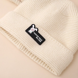 Close-up of cream white knit hat featuring a cute cartoon rabbit patch and soft texture
