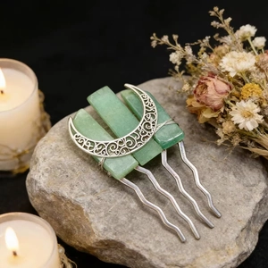 Macro shot of silver crescent moon and green crystals hair comb on a grey stone