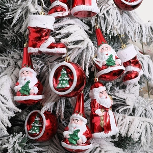 Red Santa Claus and boots ornament set on snowy Christmas tree with painted baubles