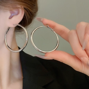 Detailed view of large silver-toned minimalist hoop earrings with a polished mirror finish