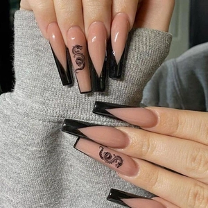 Detailed view of long coffin press-on nails with nude base, black V-tips and dragon art
