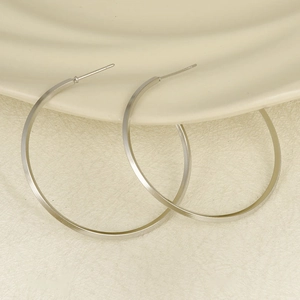 Dettaglio macro di orecchini a cerchio in acciaio 304 argento su piatto in ceramica