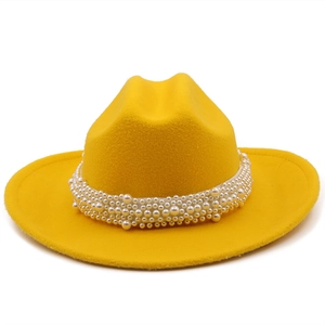 Detail of a bright yellow fedora hat featuring a decorative white faux pearl band