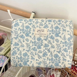 Quilted blue floral cotton cosmetic bag with zipper and ribbon on white metal basket