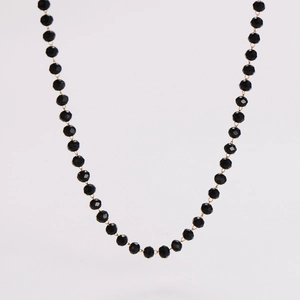 Macro shot of faceted black beads and gold links on a minimalist beaded necklace