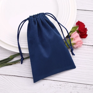 Dark blue velvet drawstring pouch for jewelry packaging on a decorative wooden desk