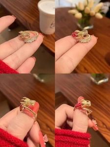 Vistas detalladas de un anillo de dragón dorado con esmalte rojo y piedras brillantes