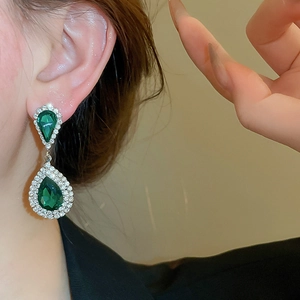 Close-up of green teardrop earrings with silver setting and sparkling rhinestones