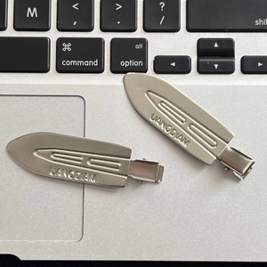 Macro detail of silver metal hair clips with geometric grooves on a laptop surface
