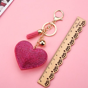 Pink heart keychain with rhinestones and tassel measured with a wooden ruler