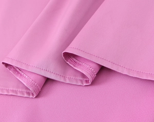 Détail de la texture du tissu en satin rose et des coutures de haute qualité