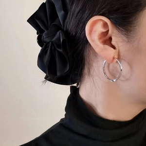 Detail of S925 silver large hoop earrings with diamond-cut texture and black bow hair accessory