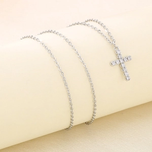Detailed view of silver cross pendant with sparkling zircons on a delicate chain