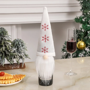 Detail of a white knitted gnome wine bottle cover with red snowflake embroidery