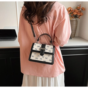 Dettaglio di una borsa a tracolla con stampa a fiocco bianco e nero indossata da una modella