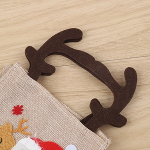 Christmas burlap gift bag with reindeer antlers and Santa applique on wooden desk