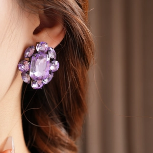 Gros plan d'un mannequin portant des boucles d'oreilles fleurs en cristal violet vintage