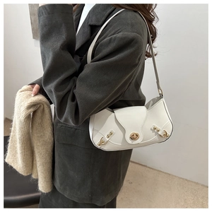 White semi-circle armpit bag with gold lock and rivets worn over green corduroy blazer