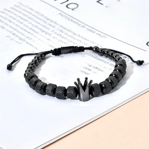 Detail of black beaded bracelet featuring a crown charm and knurled metal textures