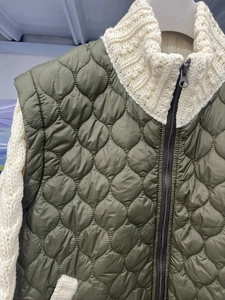 Detailed view of olive green quilted vest layered over beige chunky cable knit cardigan
