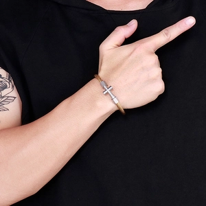 Two-tone steel wire cable bracelet with a silver cross pendant worn on a wrist