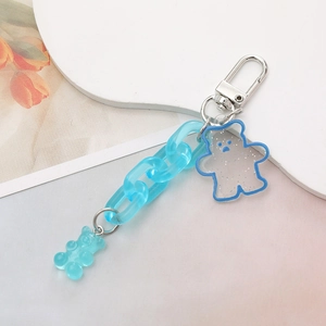 Macro detail of sky blue acrylic chain and translucent bear charms on a keychain