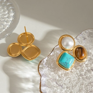 Detailed view of geometric gold earrings featuring natural stone, tiger eye and pearl inlay