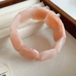 Macro detail of peach acrylic beads on elastic bracelet inside a beige velvet jewelry box