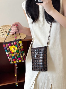 Detail view of handmade bohemian coconut shell woven mini bags with flower decor