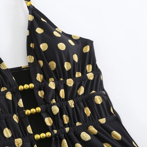 Close-up of black halter swimsuit with gold glitter polka dots and bead details