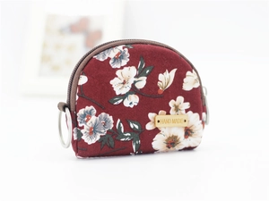Detailed close-up of dark red floral fabric coin purse with handmade wooden label