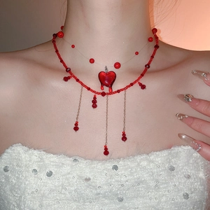 Detail of red crystal beaded necklace featuring heart pendant and cascading tassels