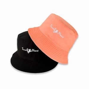 Detail of reversible bucket hats in black and coral orange with True Heart embroidery