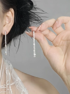 Macro detail of silver long tassel earrings with sparkling zircon and pearl accents