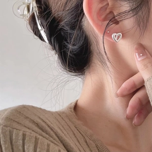 Close-up of 925 silver hollow heart-shaped hoop earring worn by a model