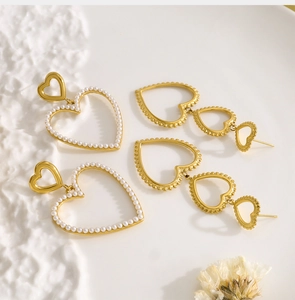 Detailed macro view of 18K gold heart earrings with pearl inlay and beaded textures