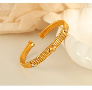 Detailed macro view of gold clover bangle with white zircon inlays and textured finish