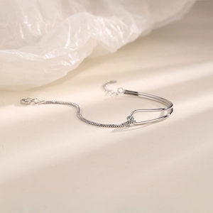 Detail of silver geometric chain bracelet featuring sleek curved bars and a toggle knot design